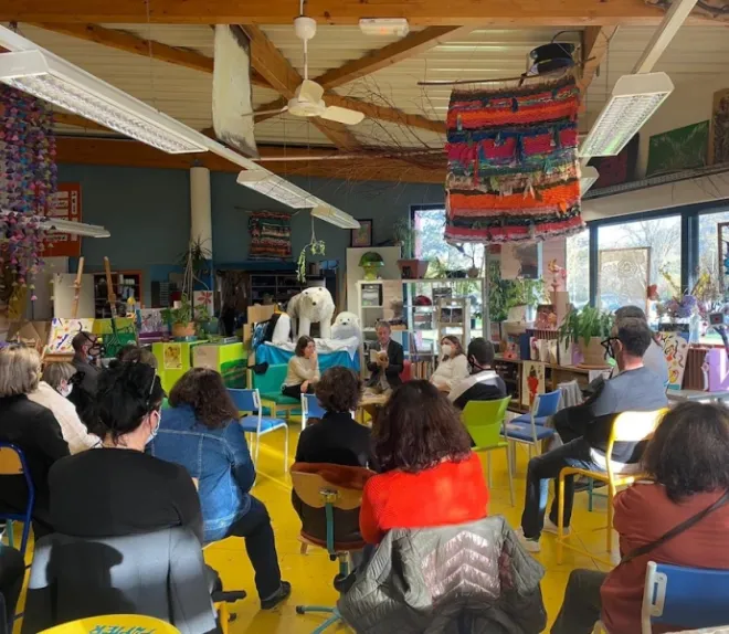 Public réuni dans un espace artistique pour une discussion ou une rencontre avec plusieurs intervenants.