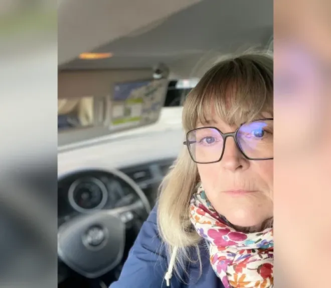 Personne portant des lunettes et un foulard, photographiée à l’intérieur d’une voiture.