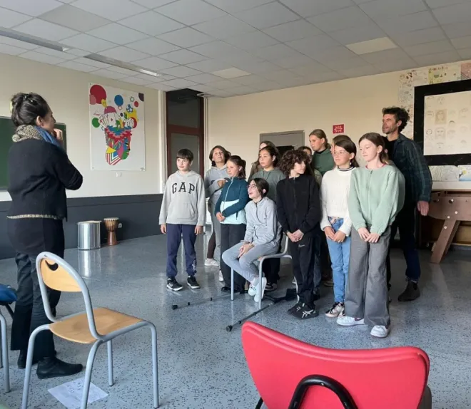 Groupe d’enfants et d’adolescents participant à une activité encadrée dans une salle de classe, face à une animatrice.
